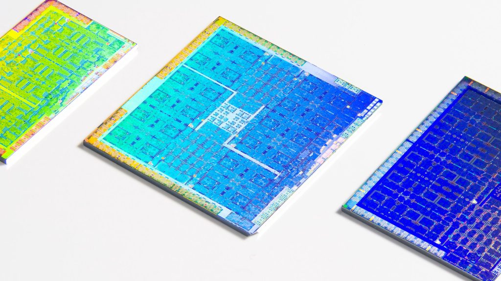 Three colorful GPUs with their packaging cleanly removed laying on a white surface. Credit: Fritzchens Fritz